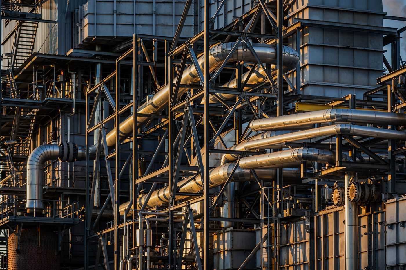 Steel structure and insulated pipework of an industrial plant at sunset